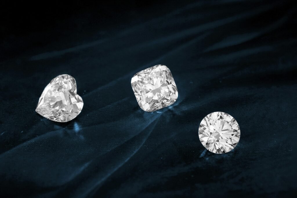 Three exquisite diamonds featuring heart, cushion, and round cuts displayed on dark fabric.